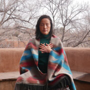 Woman meditating outdoors wearing blanket