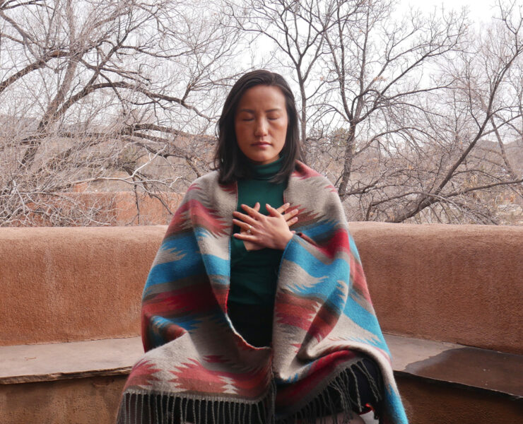 Woman meditating outdoors wearing blanket