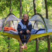 Woman sitting on tent/canopy in the woods
