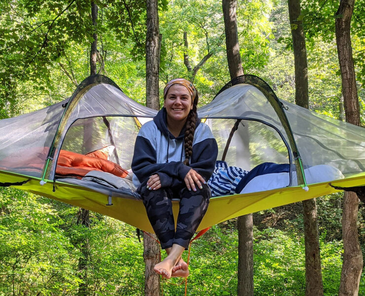 Woman sitting on tent/canopy in the woods