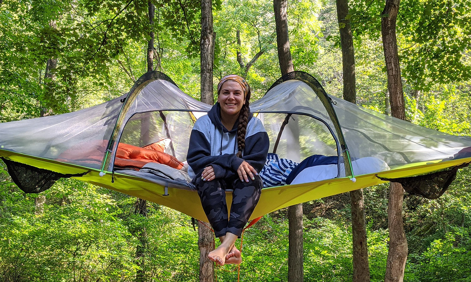 Woman sitting on tent/canopy in the woods