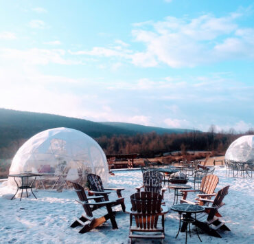 Adarondak chairs and a fire pit with igloos surrounding it in the outdoors