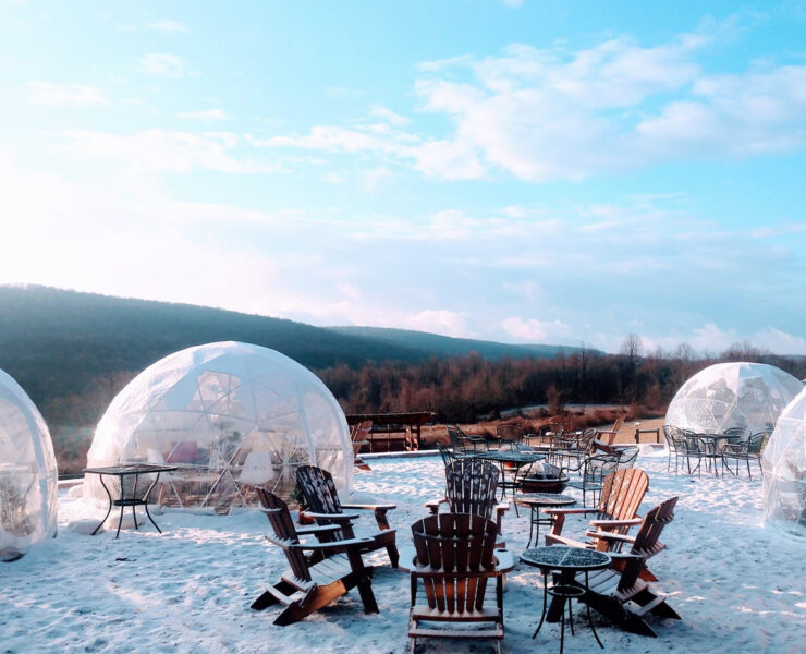 Adarondak chairs and a fire pit with igloos surrounding it in the outdoors