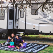 Family on a blanket outside in front of an RV