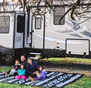 Family on a blanket outside in front of an RV
