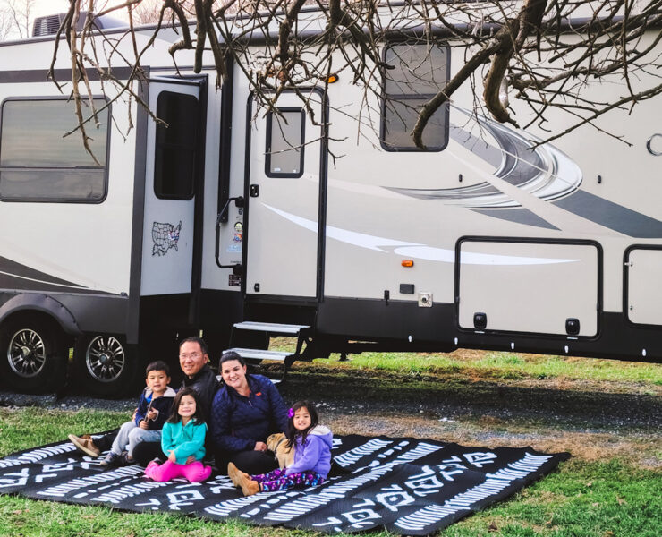 Family on a blanket outside in front of an RV
