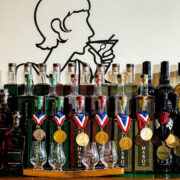Bottles lined un on a table with awards around the neck