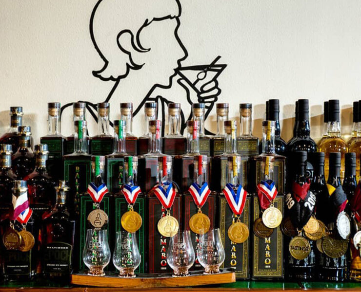 Bottles lined un on a table with awards around the neck