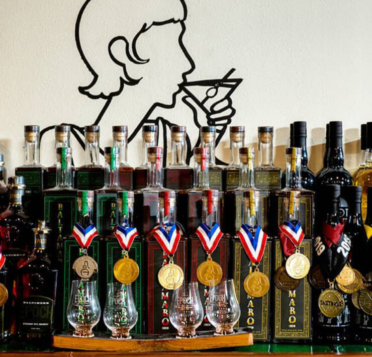 Bottles lined un on a table with awards around the neck