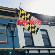 MD Flag flowing in the wind as it's held by a flag stand against a building
