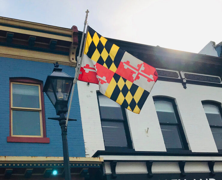 MD Flag flowing in the wind as it's held by a flag stand against a building