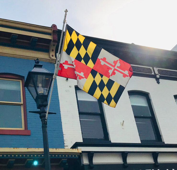 MD Flag flowing in the wind as it's held by a flag stand against a building