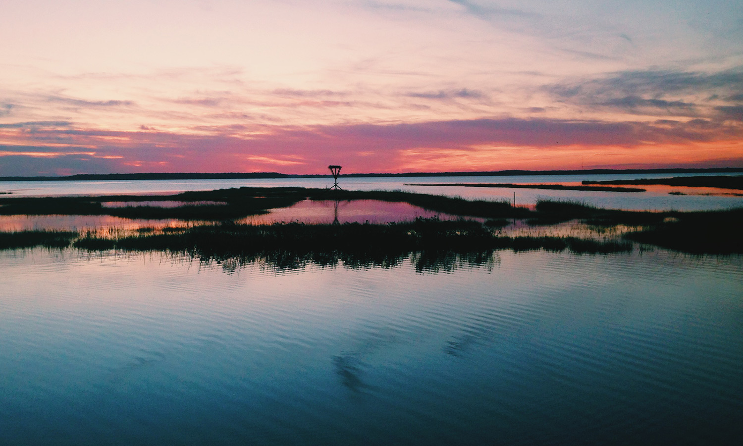 Sunset on the water with pink sky and deep blue waters