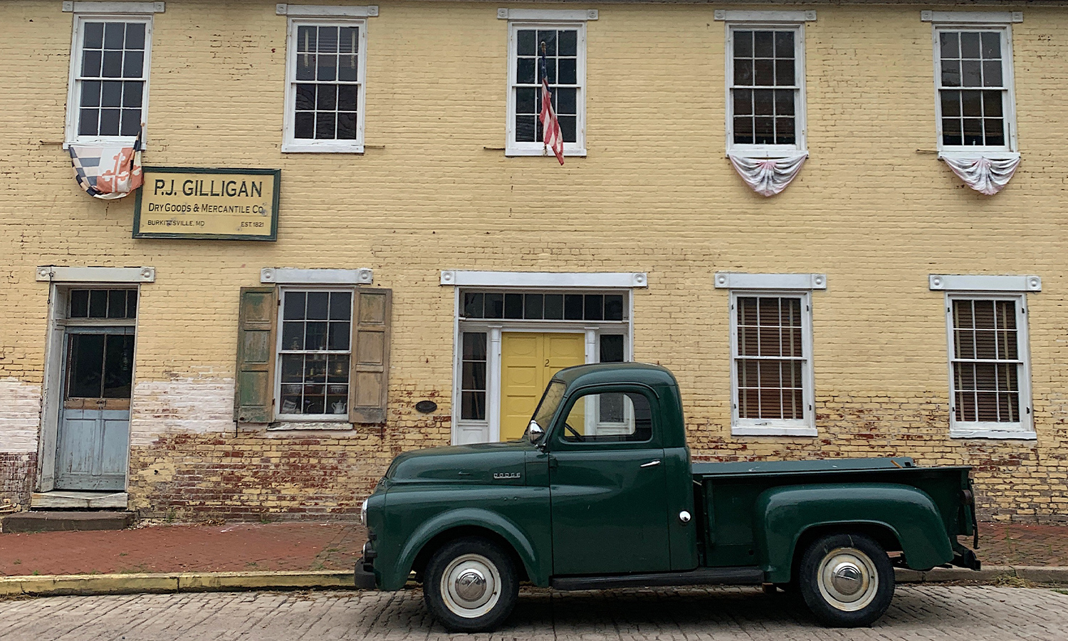PJs General StoreExterior with a green pick up truck on the road