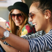 Two females in the car laughing listening to music
