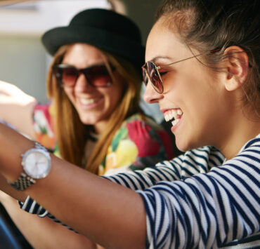 Two females in the car laughing listening to music