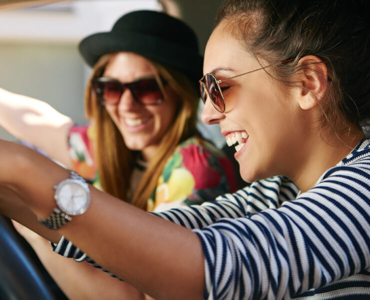 Two females in the car laughing listening to music