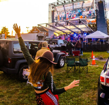 Girl dancing and looking at the stage with a band playing music on it