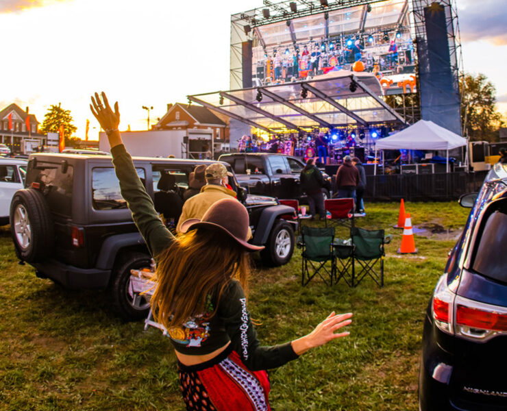 Girl dancing and looking at the stage with a band playing music on it