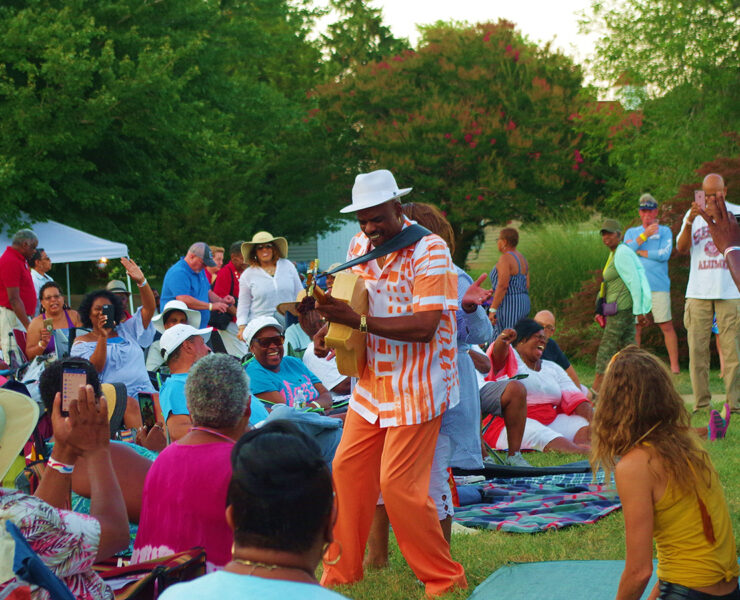 Image of a man playing a musical instrument within a crowd of people