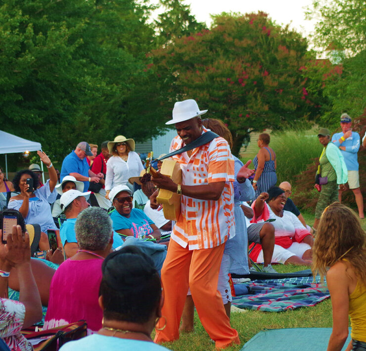 Image of a man playing a musical instrument within a crowd of people