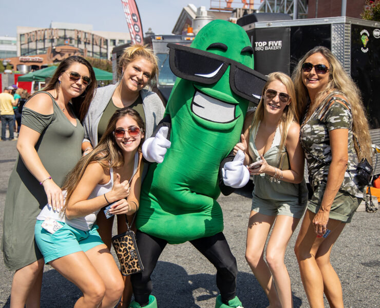 Group of people smiling at the camera with a pickle character