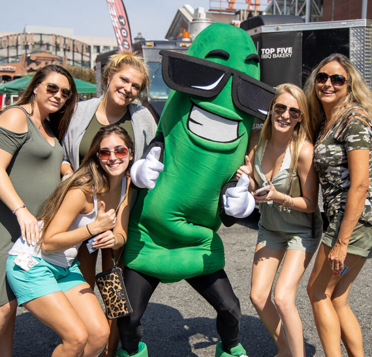 Group of people smiling at the camera with a pickle character