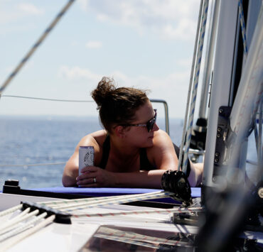 Woman laying on the front of a boat holding a White Claw