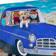 Gina and Andrew poke their heads out of a car cut-out sculpture