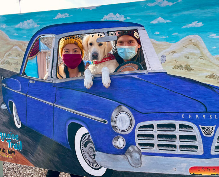 Gina and Andrew poke their heads out of a car cut-out sculpture