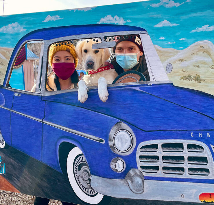 Gina and Andrew poke their heads out of a car cut-out sculpture