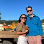 A couple standing in front of pumpkins