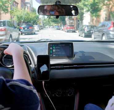 A girl driving a car with another person in the passenger seat