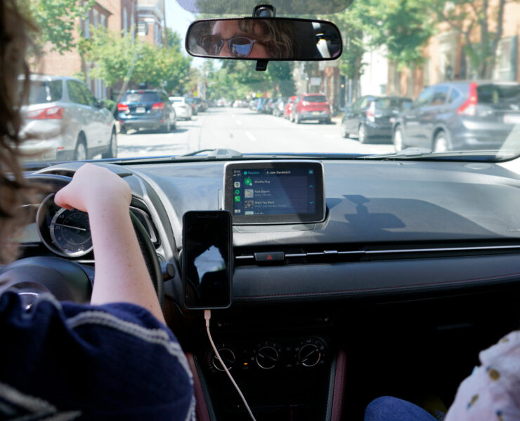 A girl driving a car with another person in the passenger seat