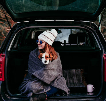 woman sitting in trunk with dog