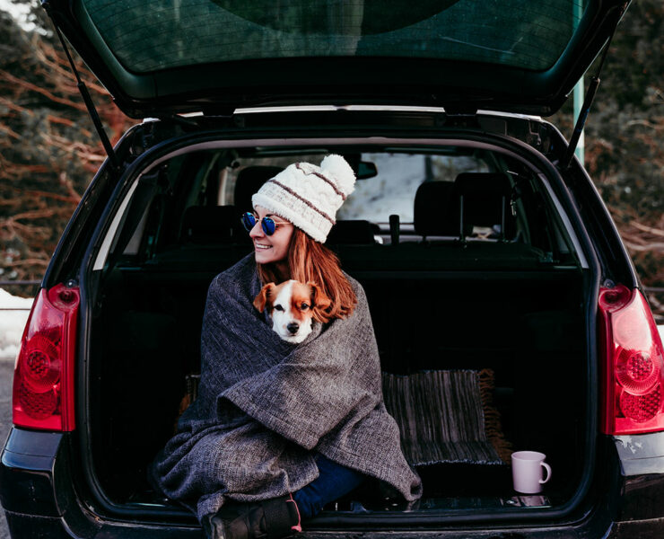 woman sitting in trunk with dog