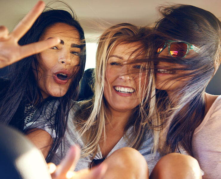 Girls with wind blowing in their hair showing peace signs