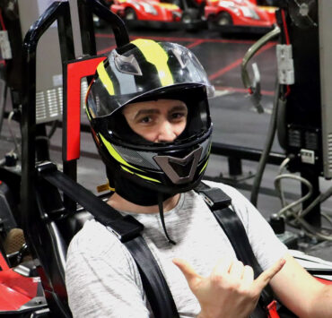 Man in go-karting helmet giving shocka hand-sign to the camera