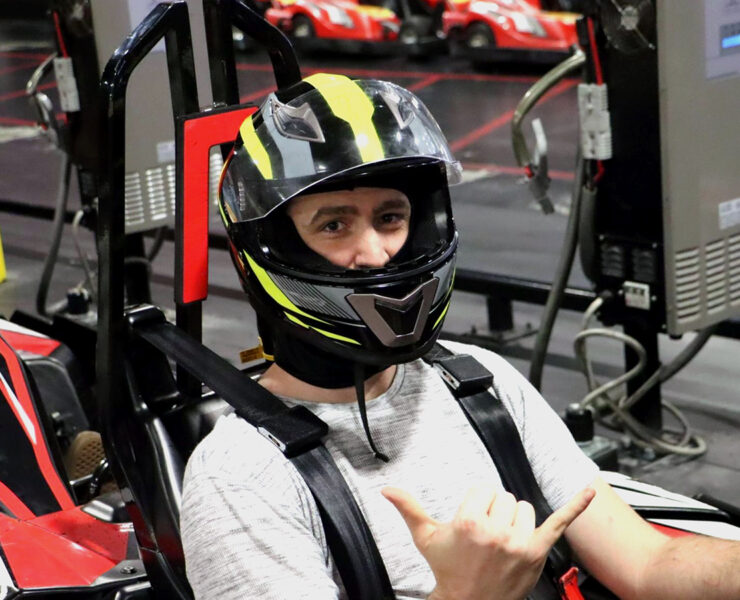 Man in go-karting helmet giving shocka hand-sign to the camera