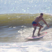 A man in swimtrunks surfing on a wave in the ocean