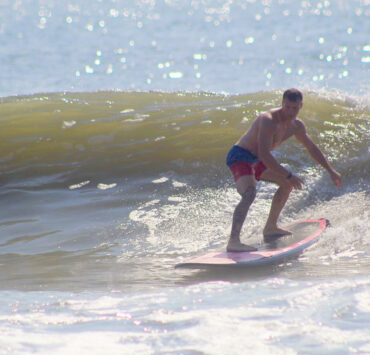 A man in swimtrunks surfing on a wave in the ocean