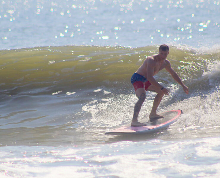 A man in swimtrunks surfing on a wave in the ocean