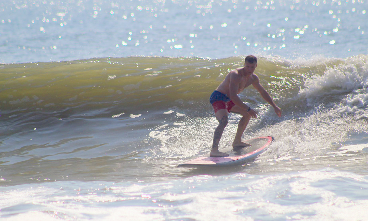 A man in swimtrunks surfing on a wave in the ocean