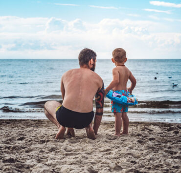 Father and son in swimtrunks on the beach