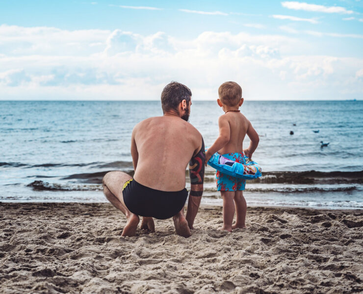 Father and son in swimtrunks on the beach