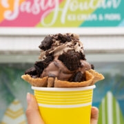 a cup of chocolate ice cream with oreos on it in front of tasty toucan sign