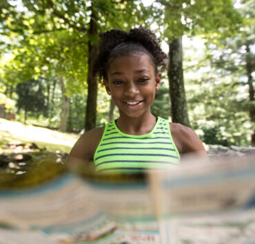 Young girl reading map in the forest