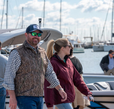 A coupe smiling while walking by boats at a dock