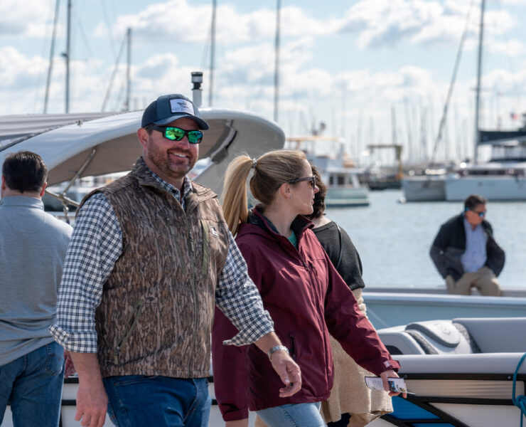 A coupe smiling while walking by boats at a dock