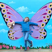 Girl poses in front of butterfly wings mural